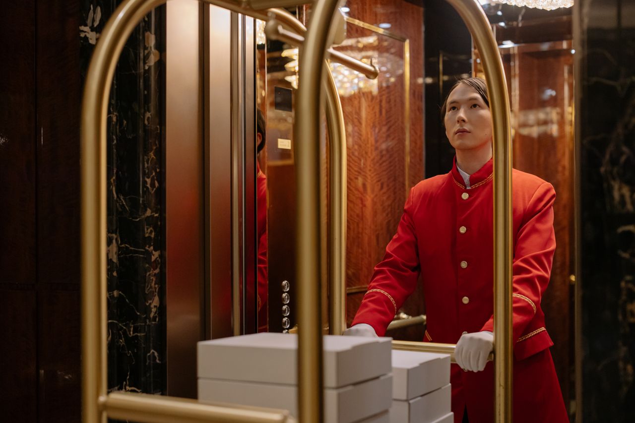 A hotel porter pushing a luggage cart through a hotel lobby