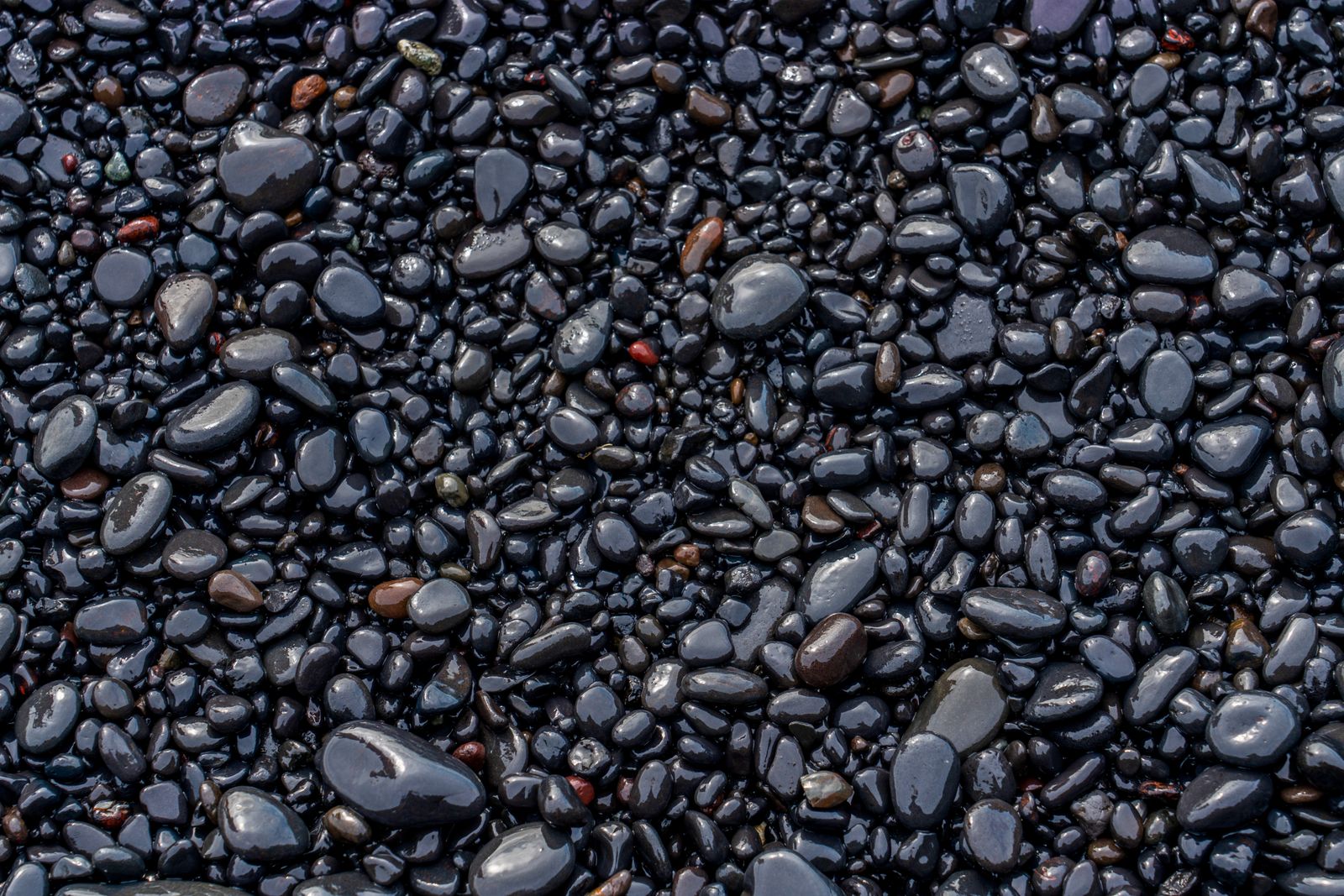 Smooth black volcanic pebbles on the shoreline at Kamari beach, Santorini