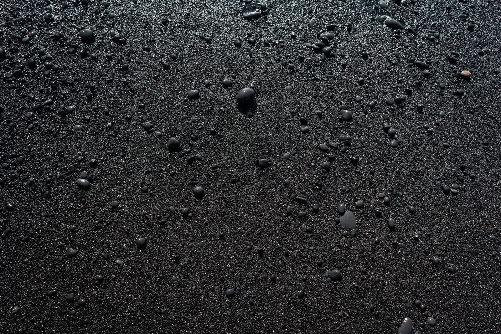 Black volcanic sand and pebbles on the beach at Perissa, Santorini