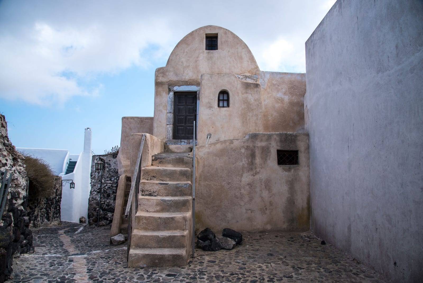 A stone house and steps on a narrow cobbled lane in Pyrgos village, Santorini